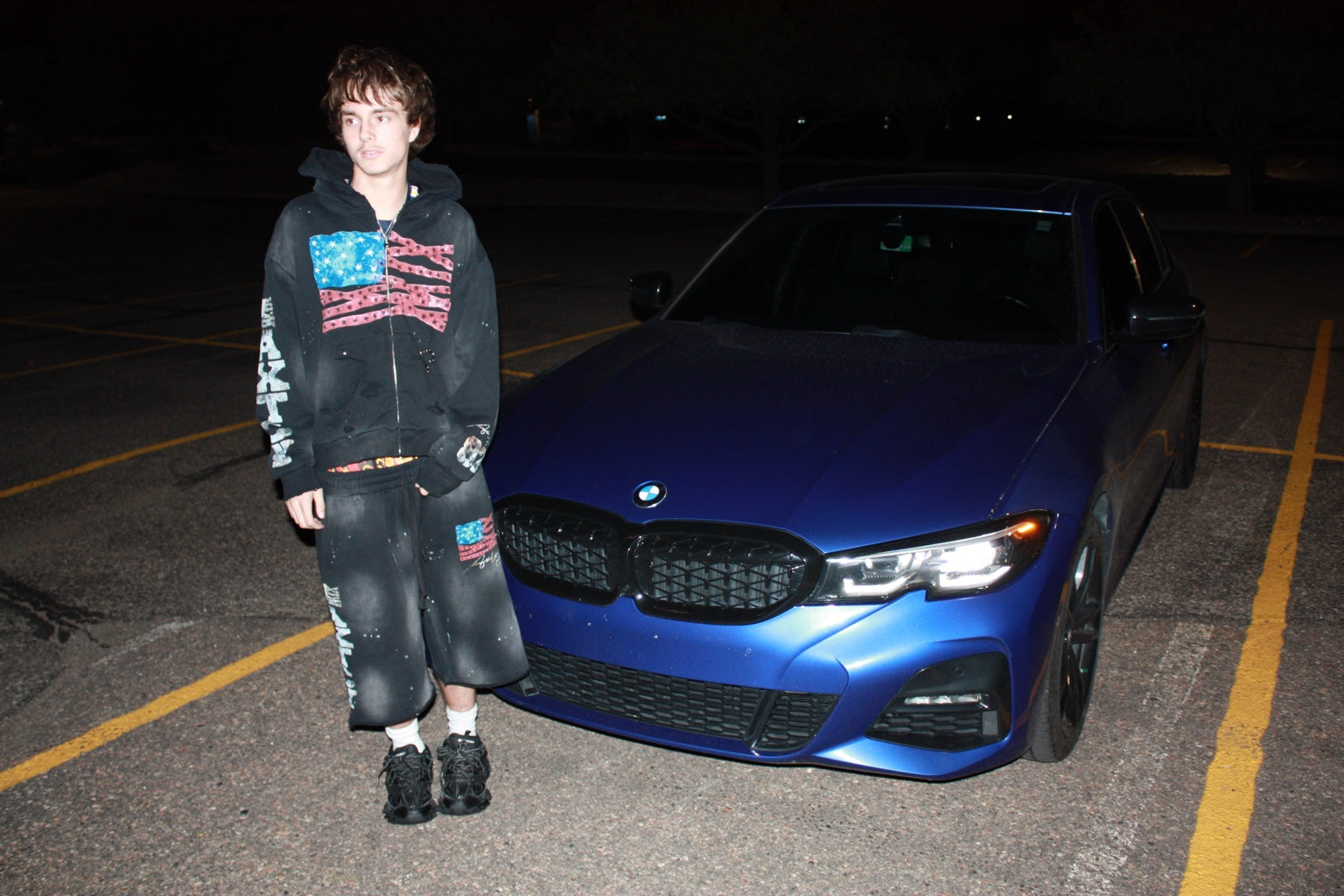 AXTCY campaign: model beside a blue BMW at night